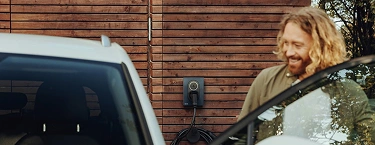 laddbox i fokus med glad man elbilsägare och elbil