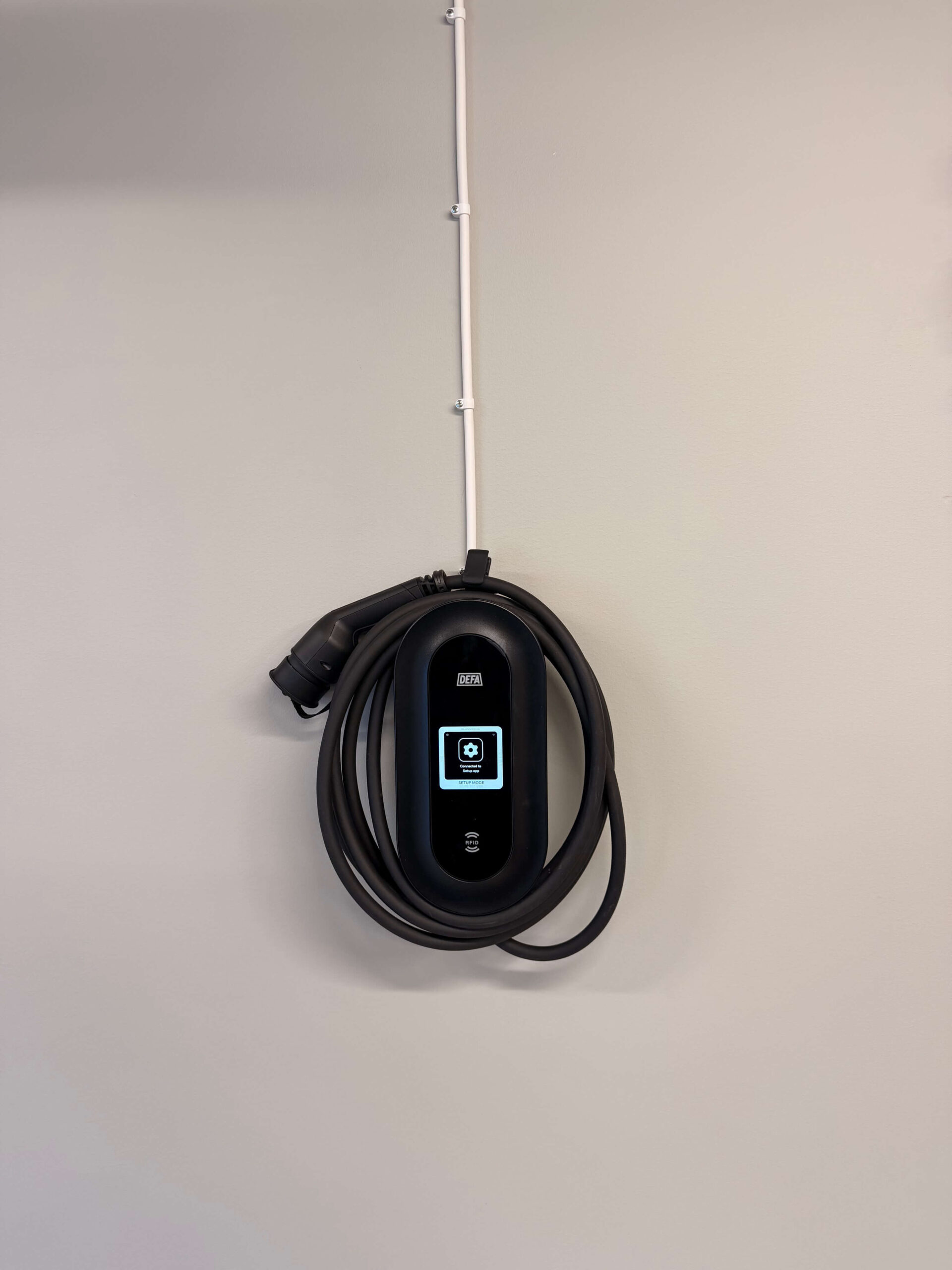 Färdig installation av DEFA Power laddbox på vägg med vit utanpåliggande kabeldragning i Sundsvall